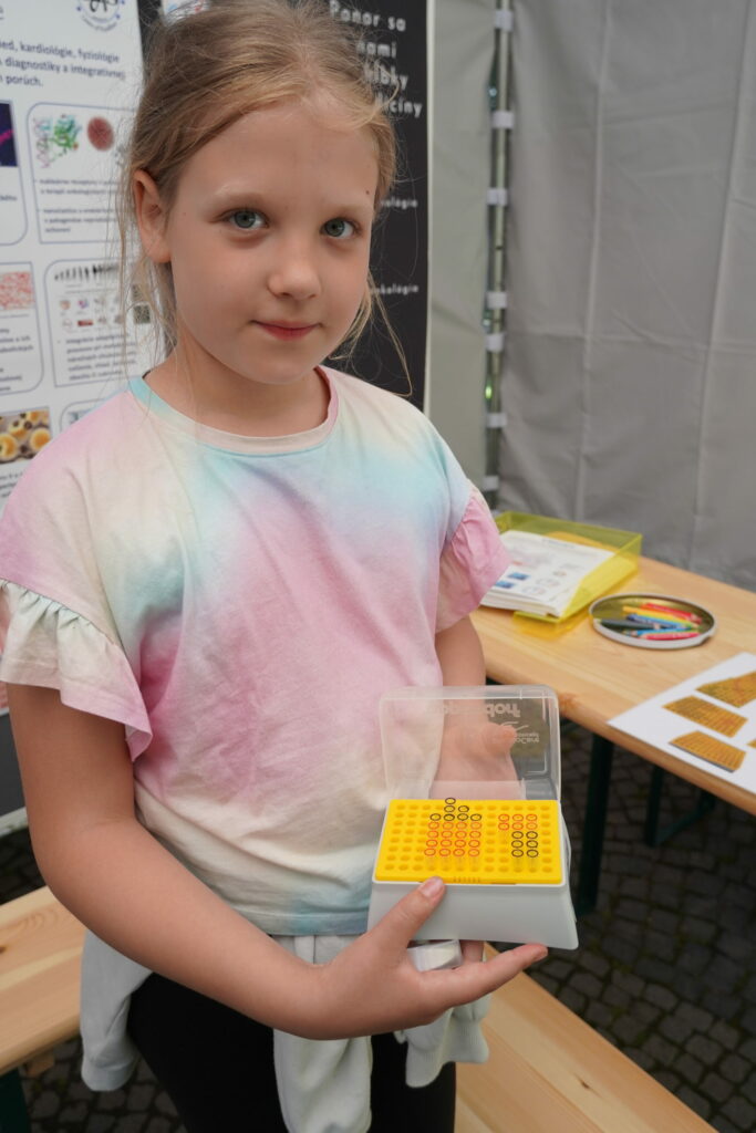 Návštevníčka podujatia My sme SAV 2024 na Hviezdoslavovom námestí v Bratislave s obrázkom zo špičiek pipiet v stánku BMC SAV.