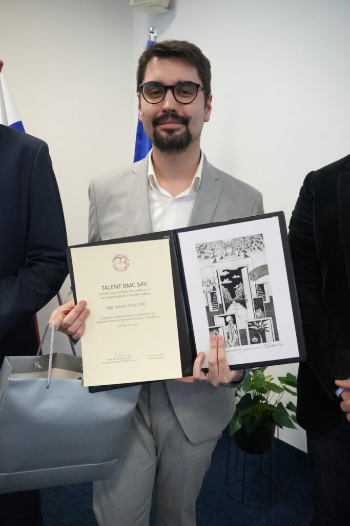 Dr. Adam Achs s diplomom a grafikou.