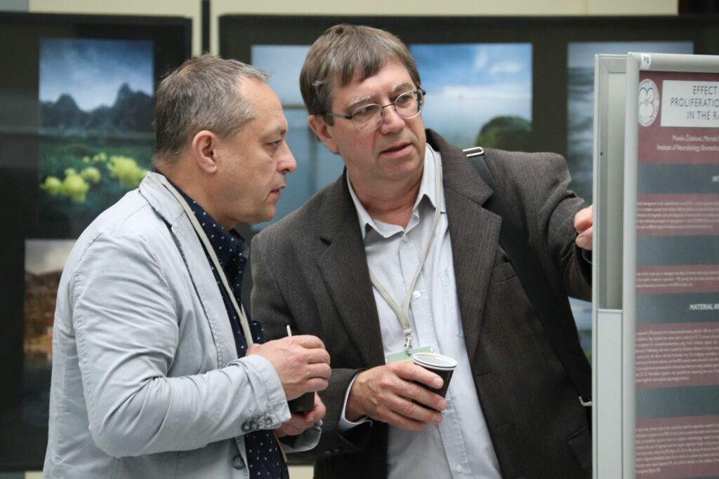 Debata vedcov pri posteri na sympóziu o neurobiológii.