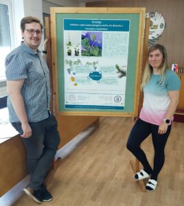Výskumníci Mgr. Jana Kemenczeiová a Mgr. Peter Alaxin z Oddelenia ekológie vírusov Virologického ústavu BMC SAV, v. v. i. stoja pred plagátom o výskume o viroidoch.
