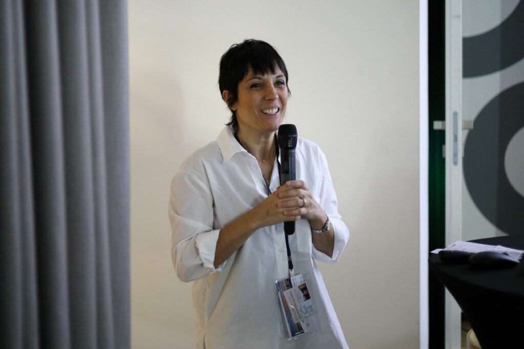 Koordinátorka projektu konferencie IMMUNO-model Eva Martínez Balibrea stojí s mikrofónom, portrét.